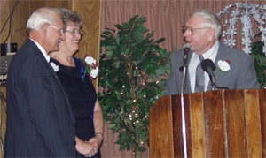 Elmer Cone, right, honors Anne and Dick Mellick as they are inducted into the International Snowmobile Hall of Fame in Grand Rapids, Minn.